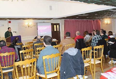 Pastor Tony preaching at the Meadow Club, and a group of church members are sitting and listening.