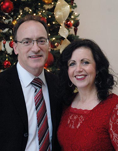 Pastor Tony and Doreen Polzella standing in front of a Christmas Tree and posing for a photo at the Church's Christmas Luncheon.