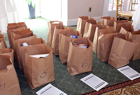 Many grocery bags lined up in rows and filled with food for Thankgiving food baskets.